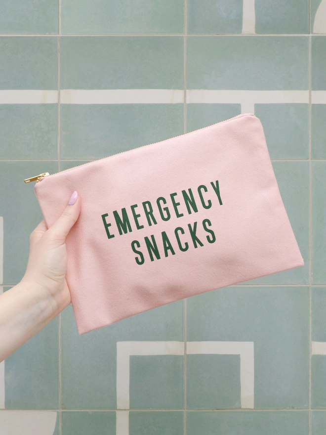 Emergency snacks pink zip pouch held out on a green background
