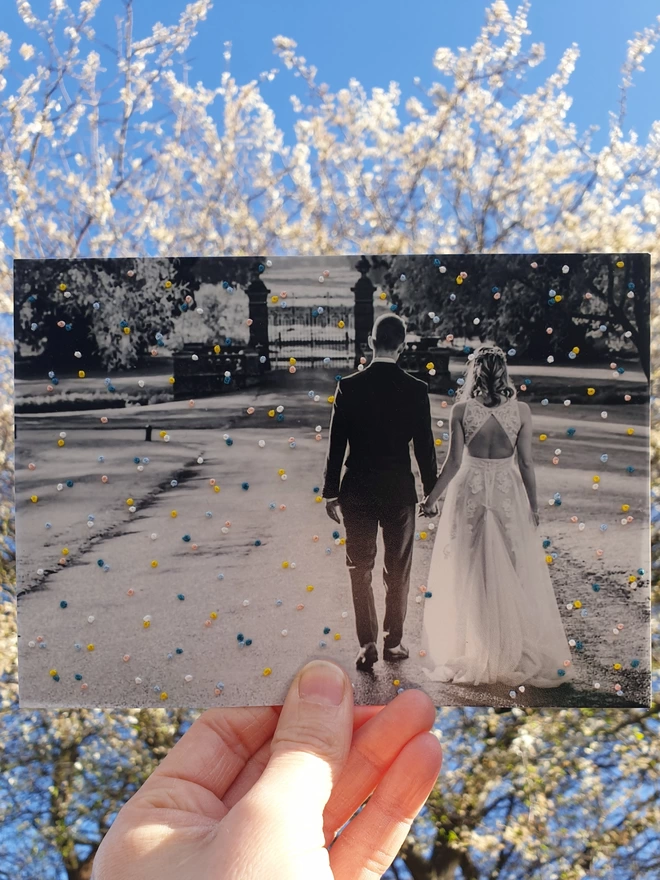 Wedding photo with hand embroidered confetti held against blossom tree