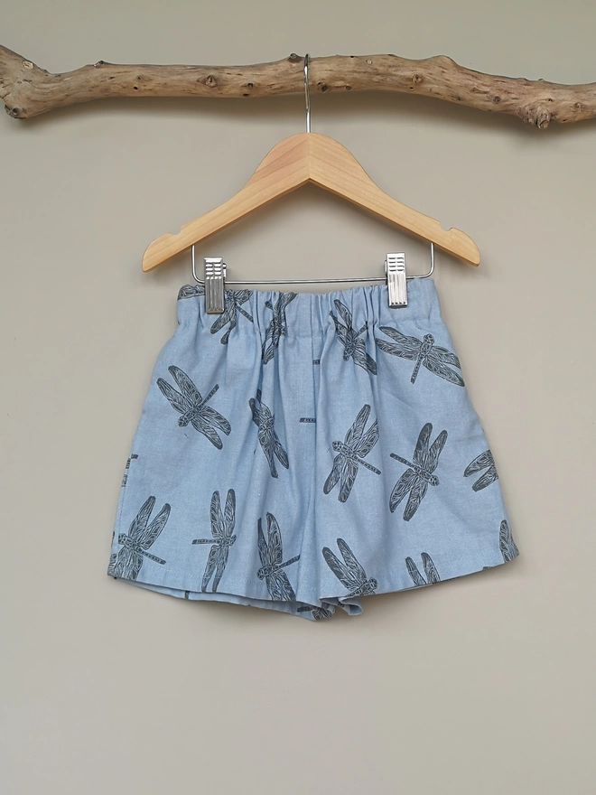 Pale Blue cotton linen lightweight unisex childrens shorts. Featuring a delicate grey dragonfly print. Simple design with elasticated waist and side seam pockets. 