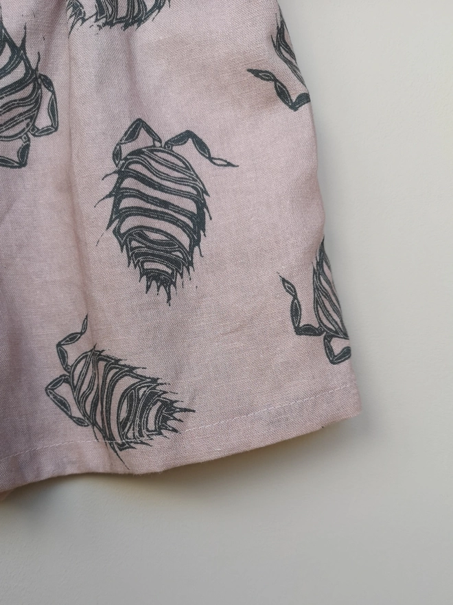 Pink cotton linen lightweight unisex childrens shorts. Featuring a delicate grey woodlouse print. Simple design with elasticated waist and side seam pockets. 