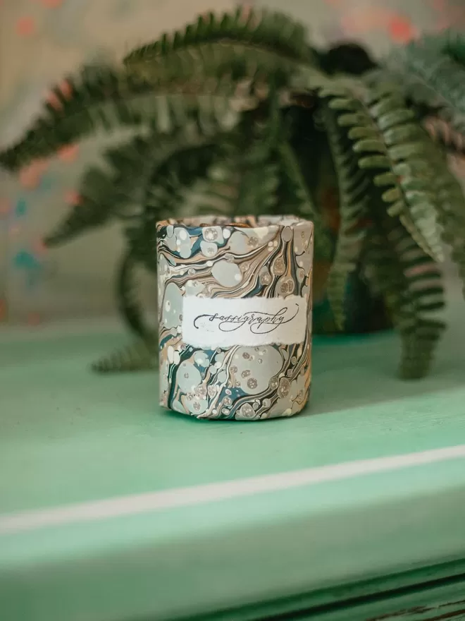 Sassigraphy Hand Poured Scented Candle With Personalised Marbled Label seen in the marble wrapping paper.